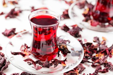 Geleneksel Türk bardaklarında hibiscus çayı ve kuru amber yaprağı. Beyaz arka planda Hibiscus çayı. Yakın plan.