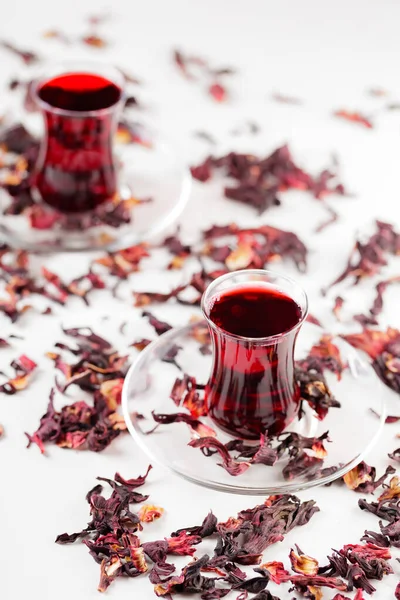 Hibiscus tea in traditional Turkish glasses and dry hibiscus petals. Hibiscus tea on a white background. Close-up