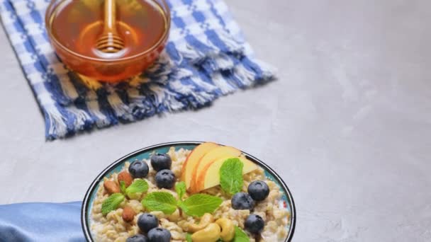 Oatmeal Porridge Berries Nuts Honey Gray Background Oatmeal Blueberries Apple — Stock Video