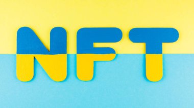 Mavi-sarı arkaplanda NFT yazıları var. Ukrayna bayrağı renginde iadesiz jeton. Ukrayna kripto sanat konsepti. Üst görünüm