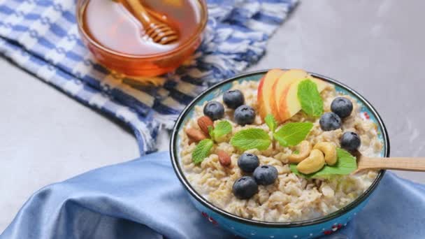 燕麦粥 带有浆果 坚果和蜂蜜的灰色背景 燕麦片 苹果片和新鲜薄荷在碗里 健康食品概念 — 图库视频影像