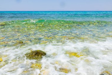 Turkuaz deniz ve mavi gökyüzü. Yazlık bir tatil köyünde deniz dalgalarıyla manzara. Yaz tatili kavramı