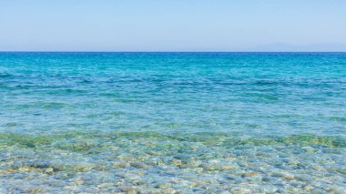 Turkuaz deniz ve mavi gökyüzü. Yazlık bir tatil köyünde deniz dalgalarıyla manzara. Yaz tatili kavramı