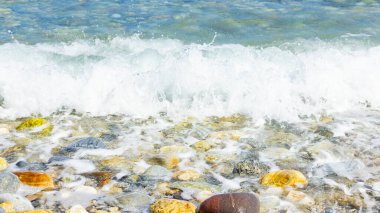 Deniz dalgası ve çakıl taşı. Yaz tatili kavramı. Kıyı şeridinde köpüklü deniz dalgası olayı. Seyahat kavramı