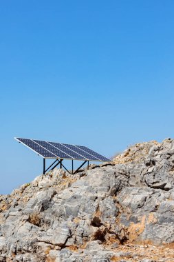 Kayalık deniz kıyısındaki güneş paneli (güneş pili). Alternatif yeşil güneş enerjisinin kaynağı. Doğadaki temiz enerji gücünü kavra. Boşluğu kopyala