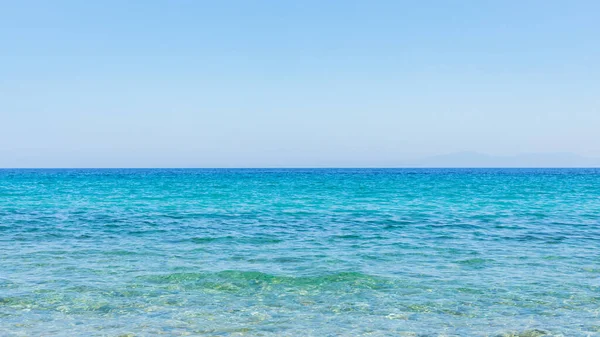 Turkuaz deniz ve mavi gökyüzü. Yazlık bir tatil köyünde deniz dalgalarıyla manzara. Yaz tatili kavramı