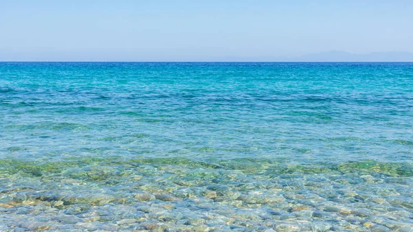 Turkuaz deniz ve mavi gökyüzü. Yazlık bir tatil köyünde deniz dalgalarıyla manzara. Yaz tatili kavramı