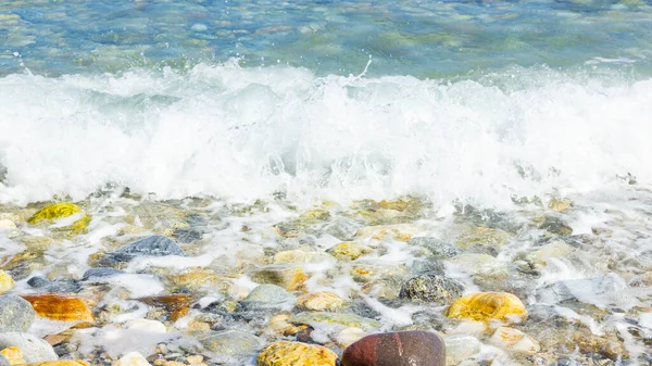Deniz dalgası ve çakıl taşı. Yaz tatili kavramı. Kıyı şeridinde köpüklü deniz dalgası olayı. Seyahat kavramı