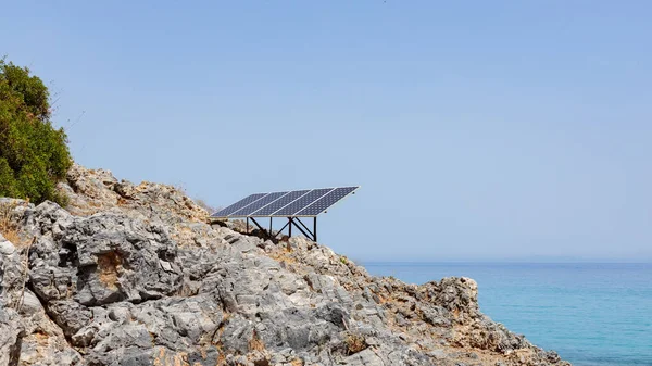 Kayalık deniz kıyısındaki güneş paneli (güneş pili). Alternatif yeşil güneş enerjisinin kaynağı. Doğadaki temiz enerji gücünü kavra. Boşluğu kopyala