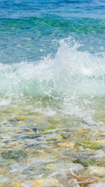 Sahildeki deniz dalgaları. Şeffaf deniz suyu ve çakıl taşları. Yaz tatili için deniz kenarı tatil beldesi