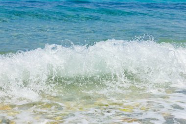 Sea waves on the coast. Transparent sea water and pebbles. Seaside resort for summer vacation
