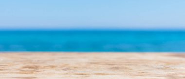 Wood table top on blur summer blue sea. Empty wooden table on the seashore and blue sky. Concept of a summer vacation at sea