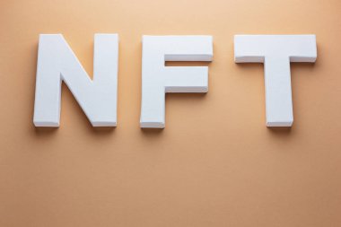 Para iadesi olmayan jeton. Bej arkaplandaki beyaz harflerden yapılmış NFT yazıtları. Toprak rengi arkaplan üzerinde NFT 3D metin. Kriptoart ve engelleme teknolojisi kavramı