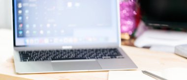 Bulanık arka planda açık dizüstü bilgisayarı olan ev ofisi. Not defteri, kalem ve dizüstü bilgisayar ahşap bir masada. Eğitim sektörü yaşam tarzı konsepti. Yumuşak odaklanma. Boşluğu kopyala