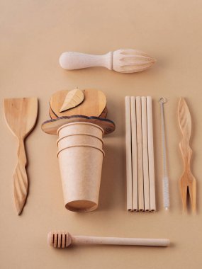 Ahşap çatal bıçak takımı ve bej arka planda tek kullanımlık bardaklar. Tahta kaplar, bambu kamışları ve temizlik fırçası. Sürdürülebilir ya da çevre dostu yaşam tarzı. Plastiksiz konsept