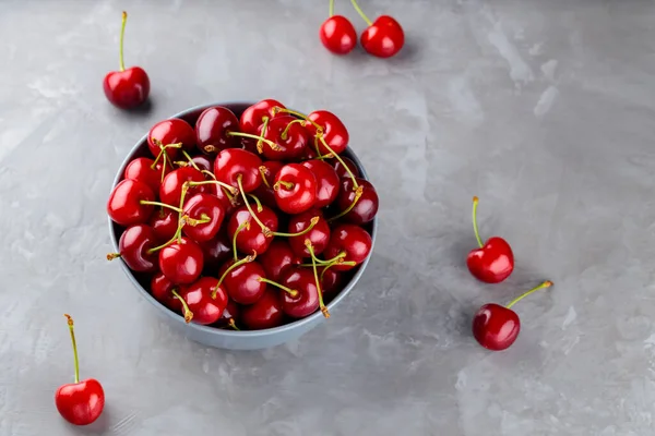 Sweet cherries in bowl. Ripe cherry on a gray background. Freshly picked cherry berries on concrete. Copy space