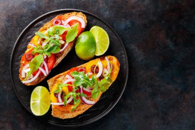 Karanlık bir arka planda vejetaryen sandviçler. Sebzeli İspanyol mezesi, yeşillik, zeytin ve limon. Siyah tabakta sağlıklı sandviçler. Üst Manzara. Boşluğu kopyala