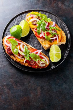 Karanlık bir arka planda vejetaryen sandviçler. Sebzeli İspanyol mezesi, yeşillik, zeytin ve limon. Siyah tabakta sağlıklı sandviçler. Üst Manzara. Boşluğu kopyala