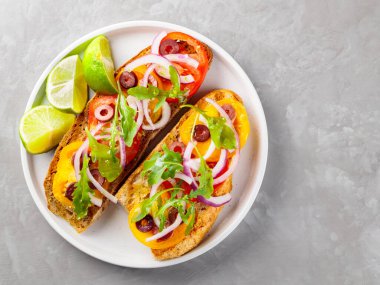 Sağlıklı vejetaryen tostları ve beyaz tabakta limon. Domatesli, yeşillikli ve zeytinli Sağlıklı açık sandviçler. Üst Manzara. Boşluğu kopyala