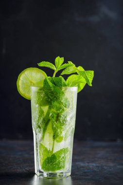 Karanlık bir arka planda mojito kokteyli. Limonlu, naneli ve buzlu yaz kokteyli. Narenciye içeceği tazeleniyor