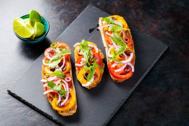 Karanlık bir arka planda İspanyol tapaları. Domates, soğan, yeşillik ve zeytinli vejetaryen tapas. Tahta tahtada sağlıklı sandviçler. Üst Manzara. Boşluğu kopyala