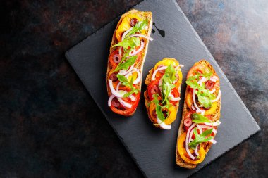 Karanlık bir arka planda İspanyol tapaları. Domates, soğan, yeşillik ve zeytinli vejetaryen tapas. Tahta tahtada sağlıklı sandviçler. Üst Manzara. Boşluğu kopyala