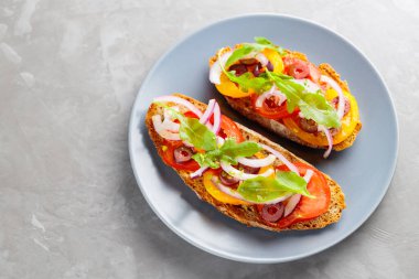 Betondaki İspanyol tapaları. Taze domates, yeşillik ve zeytinli Gri tabakta vejetaryen sandviçler. Üst Manzara. Boşluğu kopyala