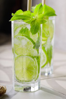 Mojito ve bar aksesuarları fayansta. İki bardak naneli ve limonlu mojito kokteyli. Bambu pipetli yaz kokteyli.