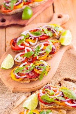 Kesme tahtasındaki İspanyol mezeleri ve limon. Domatesli, yeşillikli ve zeytinli Tahta tahtada sağlıklı açık sandviçler. Üst görünüm