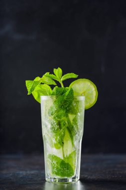 Karanlık bir arka planda mojito kokteyli. Limonlu, naneli ve buzlu yaz kokteyli. Narenciye içeceği tazeleniyor