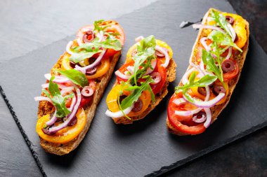 Karanlık bir arka planda İspanyol tapaları. Domates, soğan, yeşillik ve zeytinli vejetaryen tapas. Tahta tahtada sağlıklı sandviçler. Üst görünüm