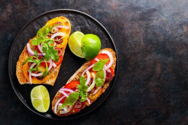 Karanlık bir arka planda vejetaryen sandviçler. Sebzeli İspanyol mezesi, yeşillik, zeytin ve limon. Siyah tabakta sağlıklı sandviçler. Üst Manzara. Boşluğu kopyala