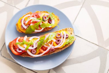 Vegetarian tapas on tile. Bruschetta with fresh tomato, greens and olives. Vegetarian open sandwiches on gray plate. Top view. Copy space