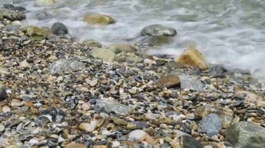 Sea waves and pebbles coast. Rocky beach pebbles on shore and rolling sea waves splashing. Close-up