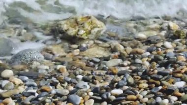 Sea waves and pebbles coast. Rocky beach pebbles on shore and rolling sea waves splashing. Close-up
