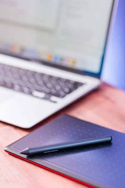 Graphic designer\'s workplace. Laptop and graphics tablet on a wooden table. Freelance work concept