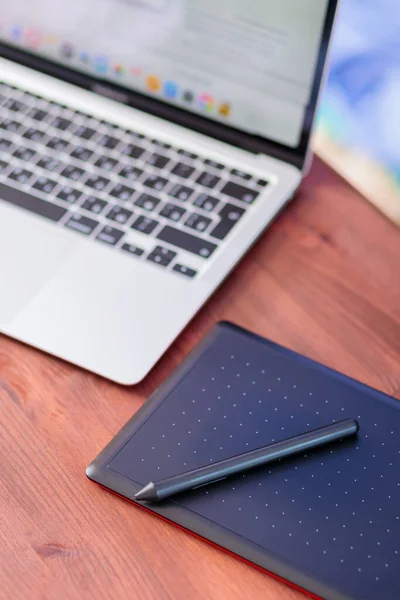 Graphic designer\'s workplace. Laptop and graphics tablet on a wooden table. Freelance work concept