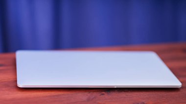 Closed laptop on a wooden table. Silvery laptop at workplace in home office. Work from home concept