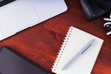 Freelancer 'ın işyeri. Laptop, akıllı telefon ve defter tahta bir masanın üzerinde. Ev idaresi ve uzaktan çalışma kavramı. Üst görünüm
