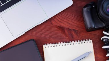 Freelancer 'ın işyeri. Laptop, akıllı telefon ve defter tahta bir masanın üzerinde. Ev idaresi ve uzaktan çalışma kavramı. Üst görünüm