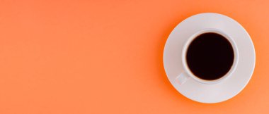 Turuncu mercan zemin üzerinde fincan üstü kahve olan beyaz fincan. Kahvaltıda sade kahve. Üst Manzara. Panoramik çekim