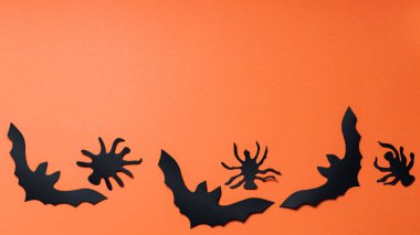 Turuncu arka planda yarasalar ve örümcekler olan Cadılar Bayramı geçmişi. Cadılar Bayramı kağıt süslemeleri. Boşluğu kopyala