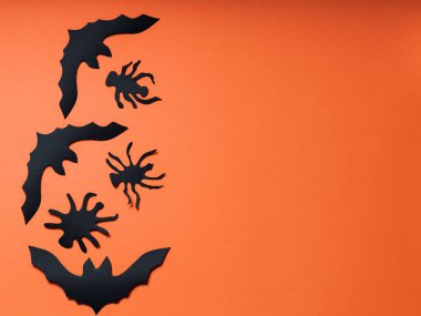 Turuncu arka planda yarasalar ve örümcekler olan Cadılar Bayramı geçmişi. Cadılar Bayramı kağıt süslemeleri. Boşluğu kopyala