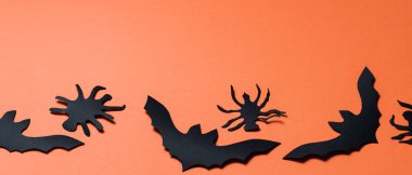 Turuncu arka planda yarasalar ve örümcekler olan Cadılar Bayramı geçmişi. Cadılar Bayramı kağıt süslemeleri. Boşluğu kopyala