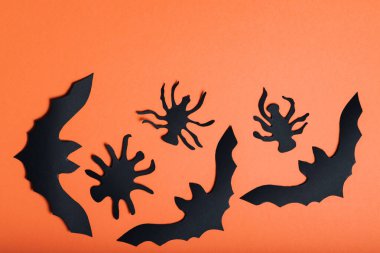 Turuncu arka planda yarasalar ve örümcekler olan Cadılar Bayramı geçmişi. Cadılar Bayramı kağıt süslemeleri. Boşluğu kopyala