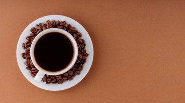 Kahverengi arka planda bir kahve fincanı. Bir fincan sade kahve ve bir fincan beyaz çay tabağı. Üst Manzara. Boşluğu kopyala