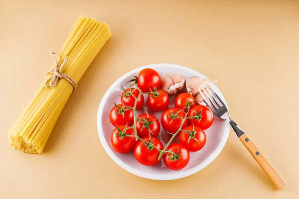 토마토와 마늘이 곁들여진 파스파 스파게티는 베이지 배경이다 날으는 파스타 위에서 — 스톡 사진