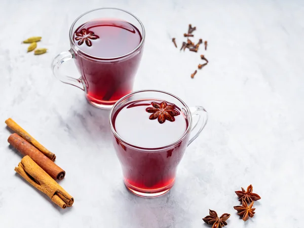 Mulled wine in cups with anise, cinnamon and cloves on concrete background. Hot drink with wine, fruits and spices. Copy space. Top view