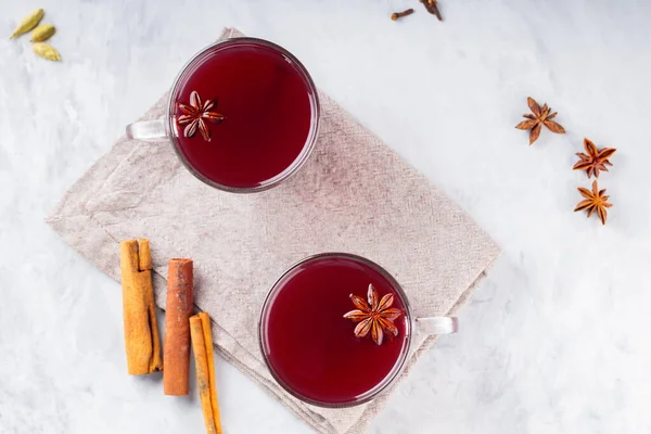 Christmas mulled wine with spices on gray concrete background. Two cups of mulled wine on a linen napkin. Winter warming wine drink concept