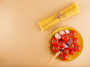 Domatesli makarna ve bej arka planda sarımsak. Çiğ makarna ve taze sebze. Üst Manzara. Boşluğu kopyala